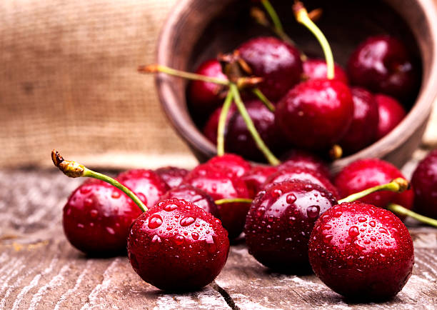 Cherries on wooden table with water drops macro background